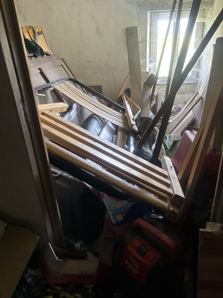 Accumulation de meubles, planches et objets divers bloquant l’accès à une pièce lors d’un débarras en situation de syndrome de Diogène.